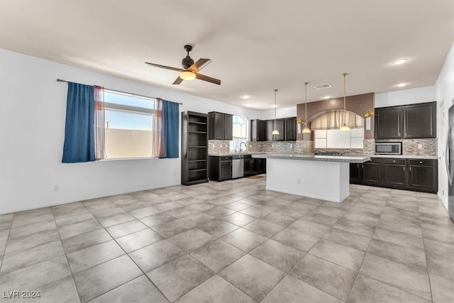 kitchen with hanging light fixtures, backsplash, a kitchen island, sink, and stainless steel appliances