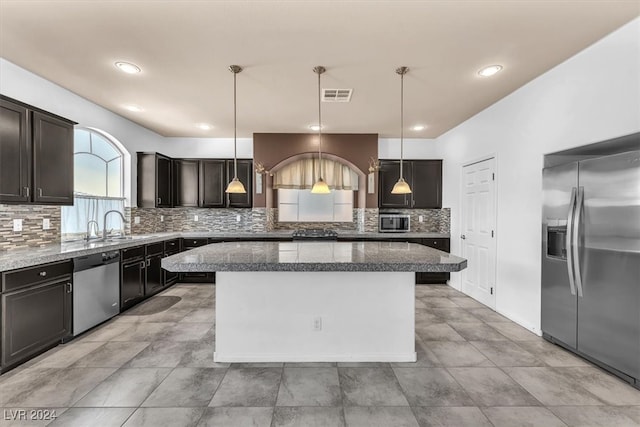 kitchen featuring appliances with stainless steel finishes, tasteful backsplash, hanging light fixtures, and a kitchen island