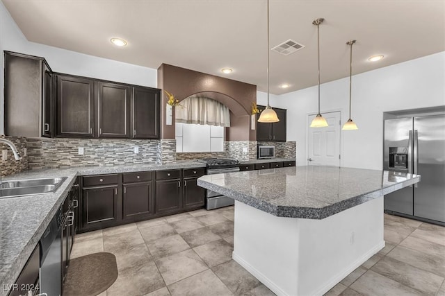 kitchen with hanging light fixtures, dark brown cabinets, sink, a center island, and appliances with stainless steel finishes