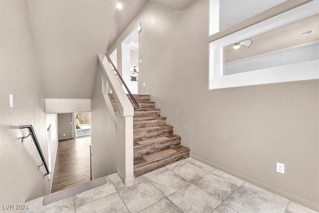 staircase with hardwood / wood-style flooring and a towering ceiling