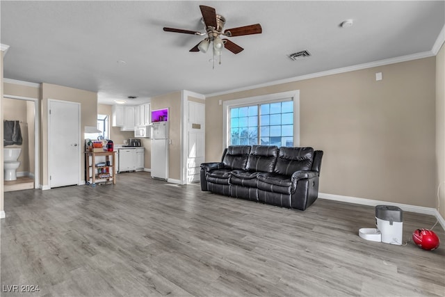 living room with light hardwood / wood-style floors, ornamental molding, and ceiling fan