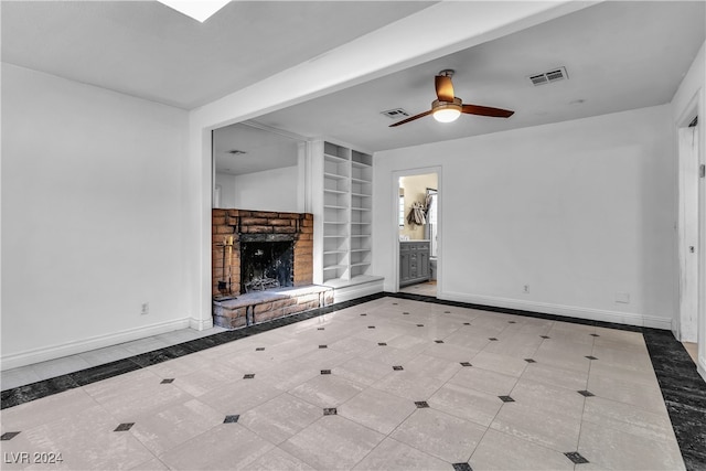 unfurnished living room featuring a stone fireplace, ceiling fan, and built in shelves