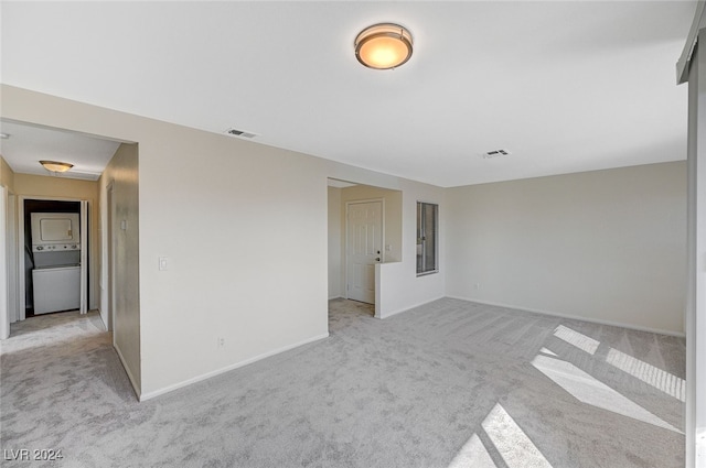 carpeted spare room with stacked washer and dryer