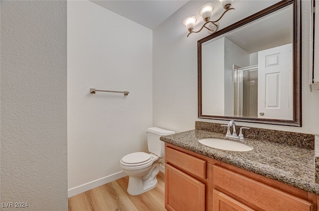 bathroom featuring a shower with door, vanity, hardwood / wood-style flooring, and toilet