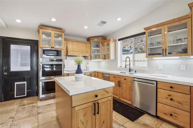 kitchen with decorative backsplash, premium range hood, stainless steel appliances, sink, and a center island