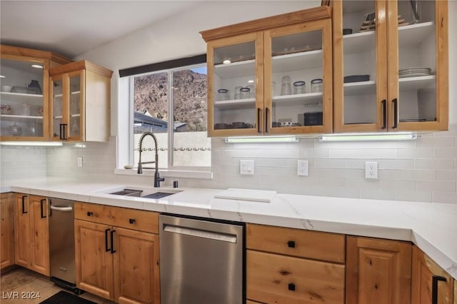 kitchen with dishwasher, backsplash, light stone counters, and sink