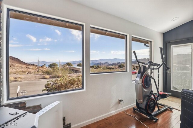 exercise area with a mountain view, wood-type flooring, and lofted ceiling