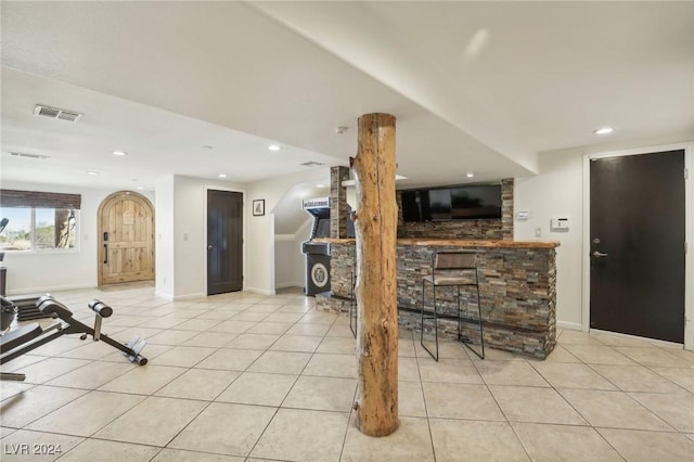 interior space featuring light tile patterned floors, ornate columns, and bar