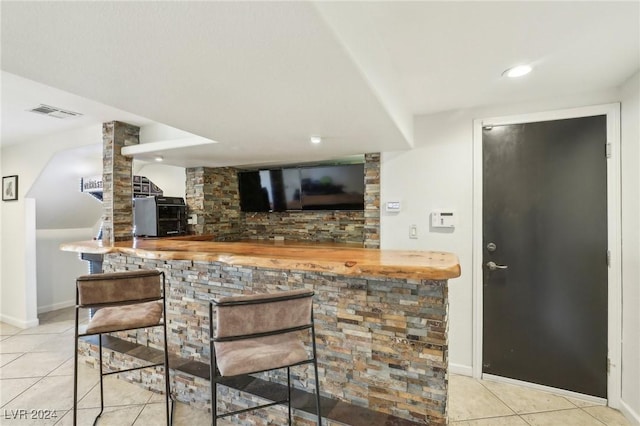 bar with butcher block counters, light tile patterned floors, and decorative columns