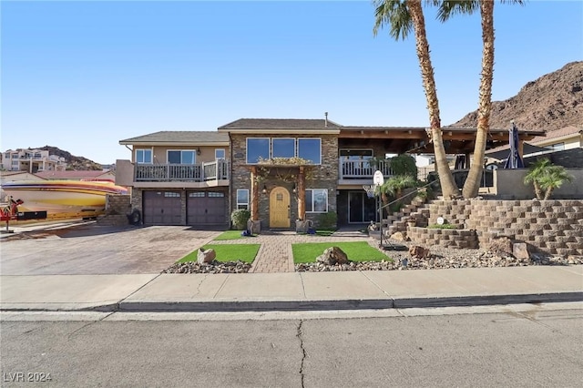 view of front of property with stucco siding, an attached garage, a balcony, and driveway