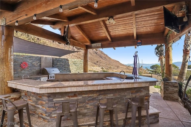 view of patio / terrace featuring exterior kitchen, a grill, a mountain view, and a bar