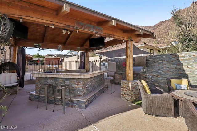 view of patio / terrace with exterior bar, a gazebo, a grill, and exterior kitchen