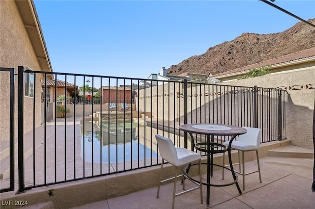 balcony with a mountain view, a patio area, and a hot tub