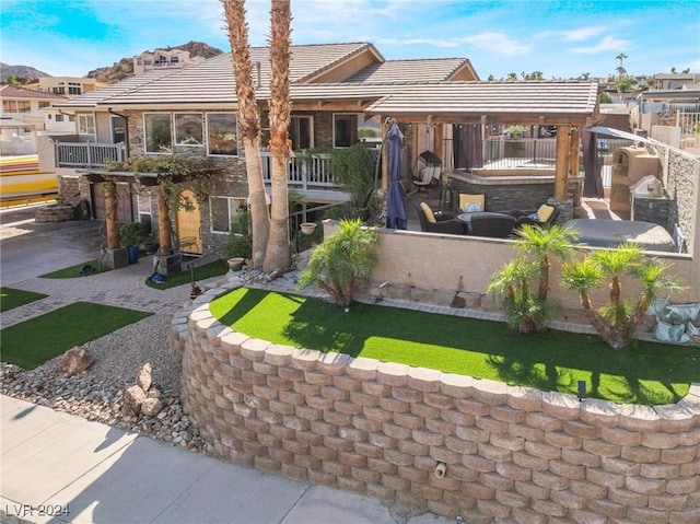 rear view of house with a patio area, stone siding, and a tiled roof