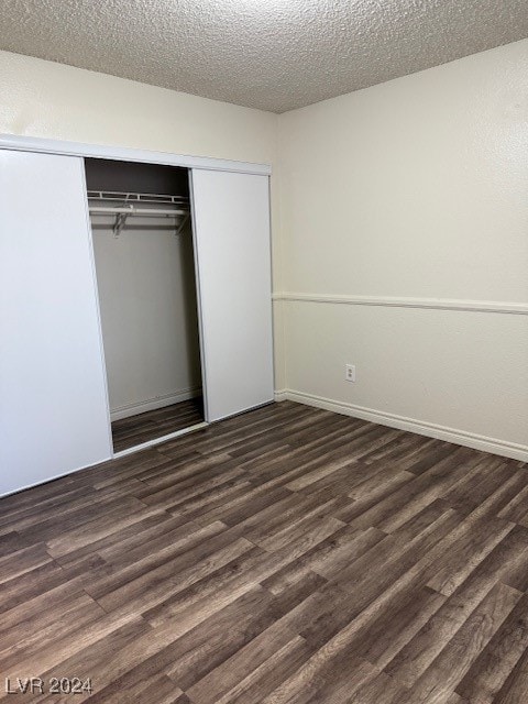 unfurnished bedroom featuring a closet, a textured ceiling, and dark hardwood / wood-style flooring