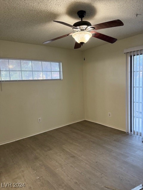 unfurnished room with a textured ceiling, dark wood-type flooring, and ceiling fan