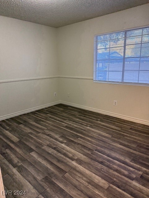 unfurnished room featuring a textured ceiling and dark hardwood / wood-style flooring