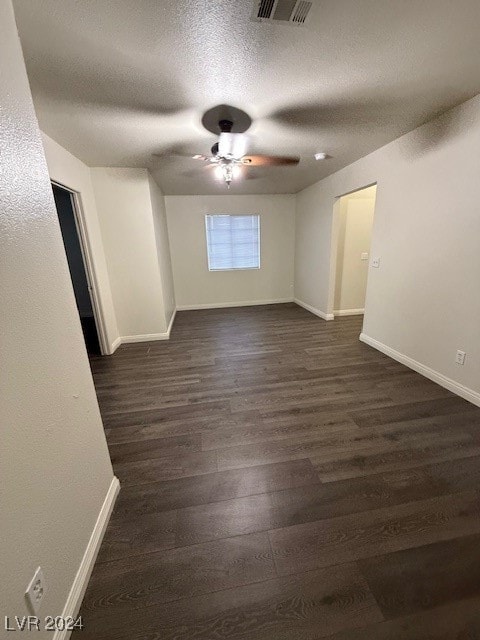 empty room featuring a textured ceiling, ceiling fan, and dark hardwood / wood-style flooring