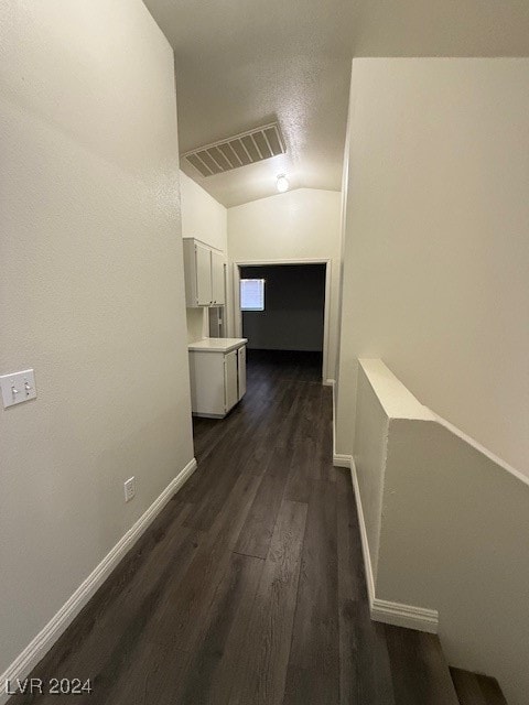 corridor featuring lofted ceiling and dark wood-type flooring