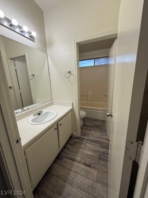 full bathroom with toilet, tiled shower / bath, vanity, and wood-type flooring