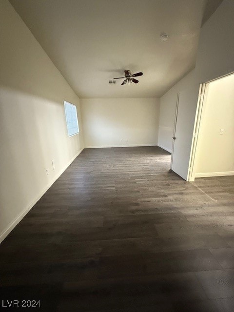 empty room with ceiling fan, vaulted ceiling, and dark hardwood / wood-style floors