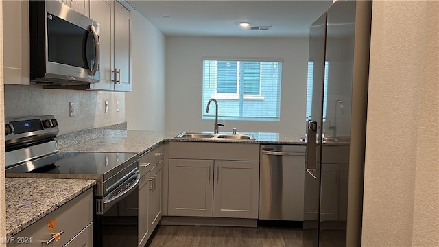 kitchen featuring appliances with stainless steel finishes, light stone countertops, sink, and gray cabinetry