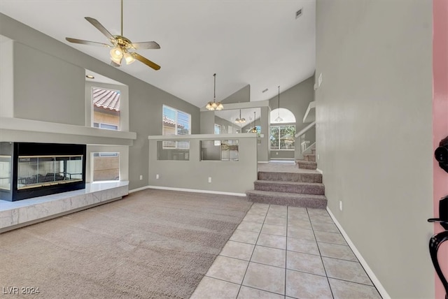 unfurnished living room featuring high vaulted ceiling, light tile patterned floors, and ceiling fan with notable chandelier