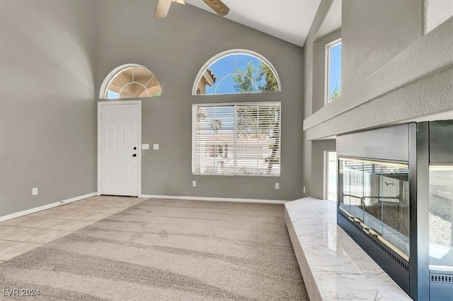 foyer entrance featuring light carpet, high vaulted ceiling, and ceiling fan