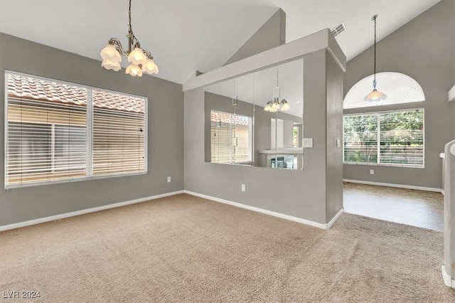 spare room featuring a notable chandelier, a healthy amount of sunlight, high vaulted ceiling, and carpet