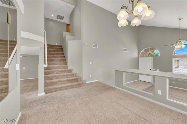 interior space featuring ceiling fan with notable chandelier, carpet flooring, and high vaulted ceiling