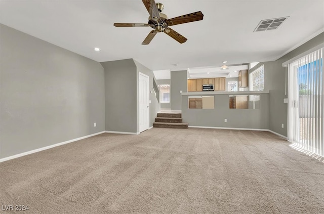 unfurnished living room featuring light carpet and ceiling fan