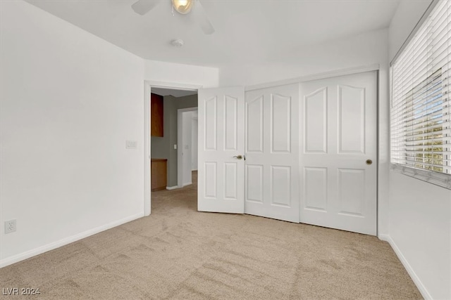 unfurnished bedroom featuring light carpet, a closet, and ceiling fan