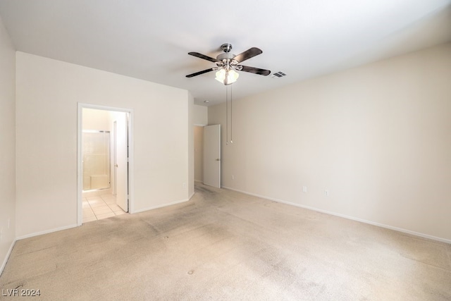 unfurnished bedroom featuring ensuite bath, ceiling fan, and light colored carpet