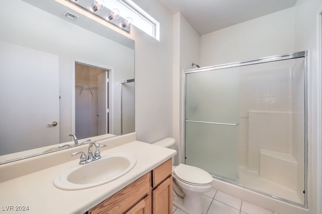 bathroom featuring tile patterned flooring, vanity, toilet, and walk in shower