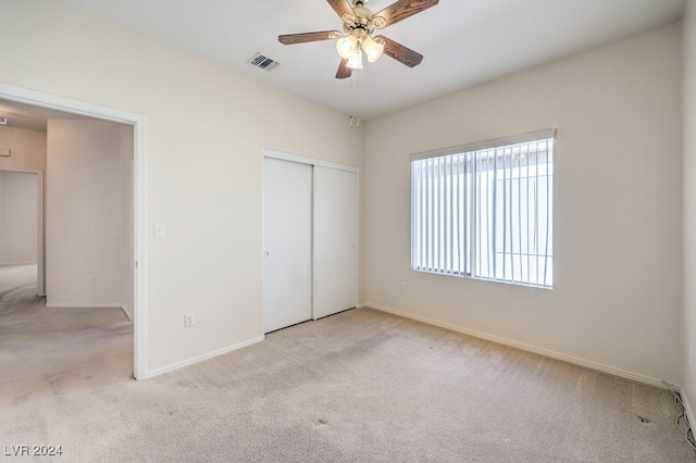 unfurnished bedroom featuring light carpet, a closet, and ceiling fan