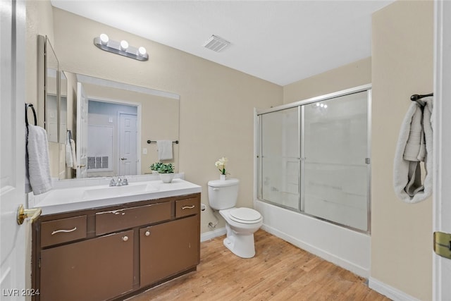 full bathroom with vanity, enclosed tub / shower combo, hardwood / wood-style flooring, and toilet