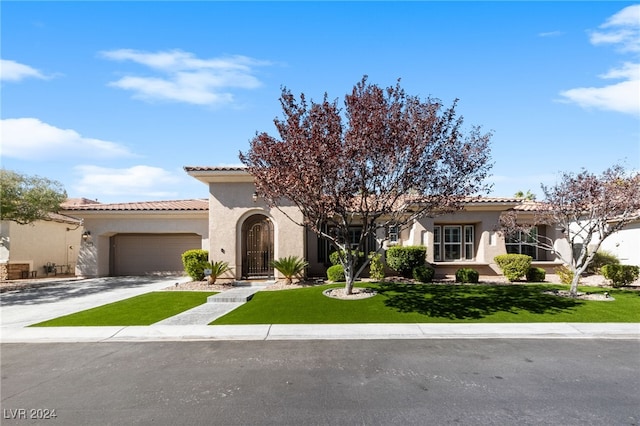 mediterranean / spanish home featuring a front yard and a garage