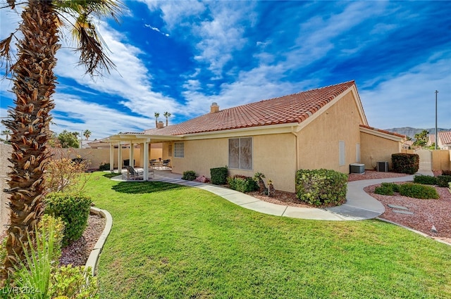 rear view of property featuring central air condition unit, a lawn, and a patio area