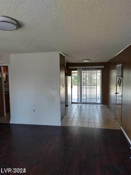 empty room with hardwood / wood-style floors, a textured ceiling, and wood walls