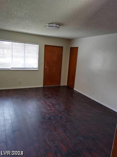 spare room featuring dark hardwood / wood-style floors and a textured ceiling