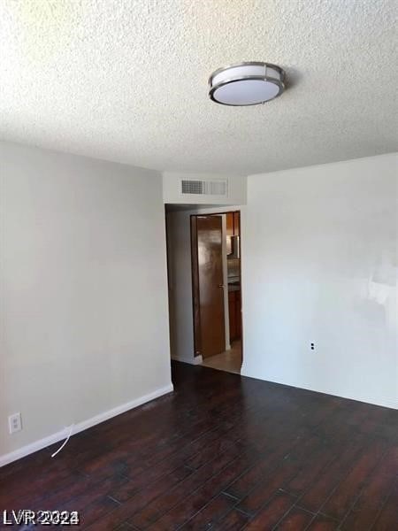 unfurnished room with dark wood-type flooring and a textured ceiling