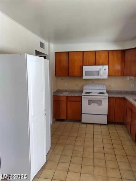 kitchen with white appliances and light tile patterned floors