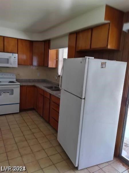 kitchen with white appliances, light tile patterned floors, and sink