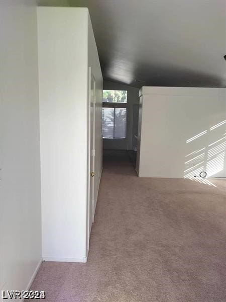 corridor featuring lofted ceiling and light colored carpet