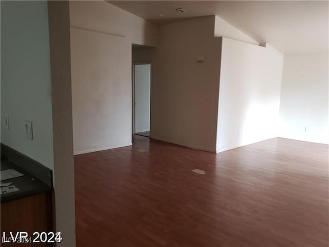 spare room with vaulted ceiling and dark hardwood / wood-style flooring