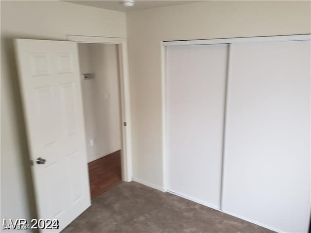 unfurnished bedroom featuring a closet and dark colored carpet