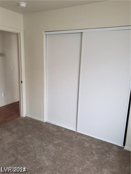 unfurnished bedroom featuring a closet and dark carpet