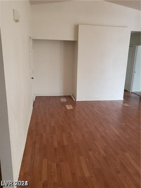 unfurnished room featuring dark wood-type flooring and vaulted ceiling