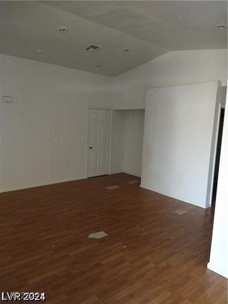 spare room featuring lofted ceiling and dark hardwood / wood-style floors