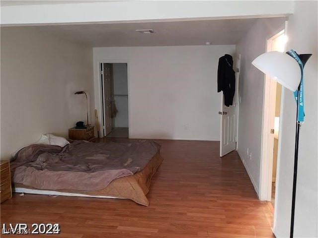 bedroom featuring a walk in closet, hardwood / wood-style flooring, and a closet